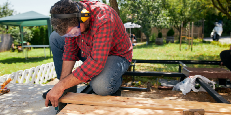 Construction worker cutting wood in a client's backyard.